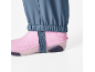 Pantaloni albaștri cu manșete elastice peste cizme de ploaie roz cu o curea.