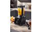 Blender negru cu supă de dovleac gata într-o bucătărie, înconjurat de ingrediente.