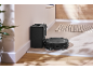 Aspirator robot negru cu stație de încărcare într-un hol modern cu podea din lemn și gresie.
