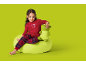 Fetiță în pijamale roșii cu textul 'DAYTIME COOKIES' stând pe un puf verde.