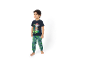Băiețel în tricou albastru închis cu un câine de desene animate și pantaloni de trening verzi cu tematică dinozauri.
