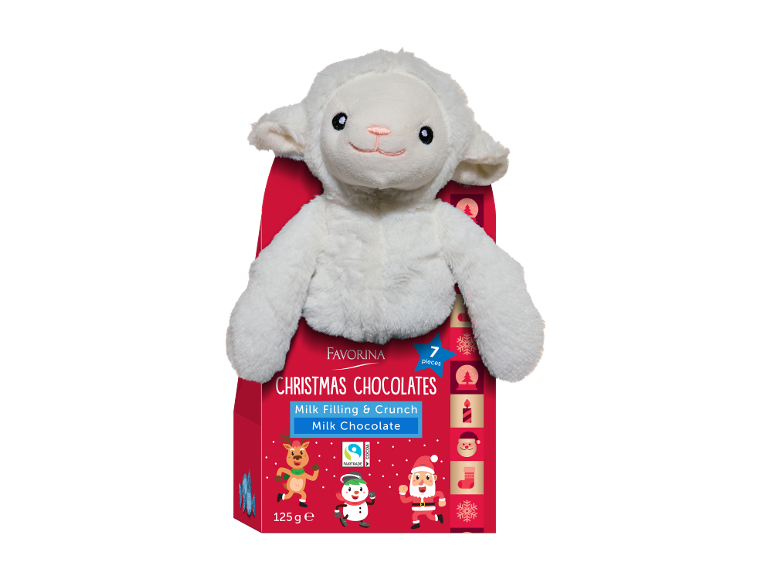 O oaie de pluș albă pe o cutie roșie de ciocolate de Crăciun cu umplutură de lapte.