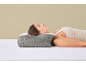 Femeie tânără dormind pe o parte pe o pernă ergonomică gri și albă.