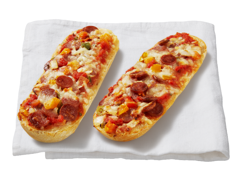 Două baghete pizza cu salam, brânză și legume pe o cârpă albă.