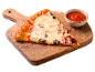 O felie de pizza cu măsline și brânză pe un tocător de lemn cu un bol de sos.