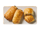 Croissante cu ciocolată aurii pe o farfurie dreptunghiulară, unul tăiat în jumătate.