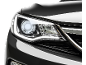Far frontal al unei mașini moderne cu lumini LED aprinse, pe fundal negru.