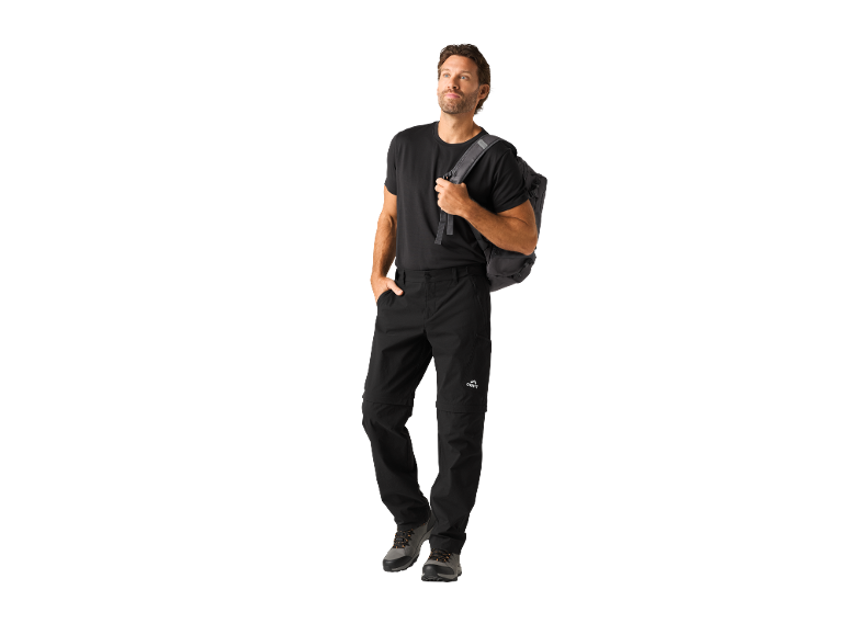 Bărbat în tricou negru, pantaloni convertibili și rucsac, privind în sus.