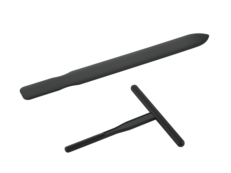Spatulă neagră din silicon și răzuitor de aluat în formă de T pe fundal negru.