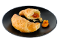 Două croissante aurii, unul cu umplutură de caise, pe o farfurie neagră.