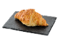 Croissant auriu cu brânză pe o placă de piatră închisă.