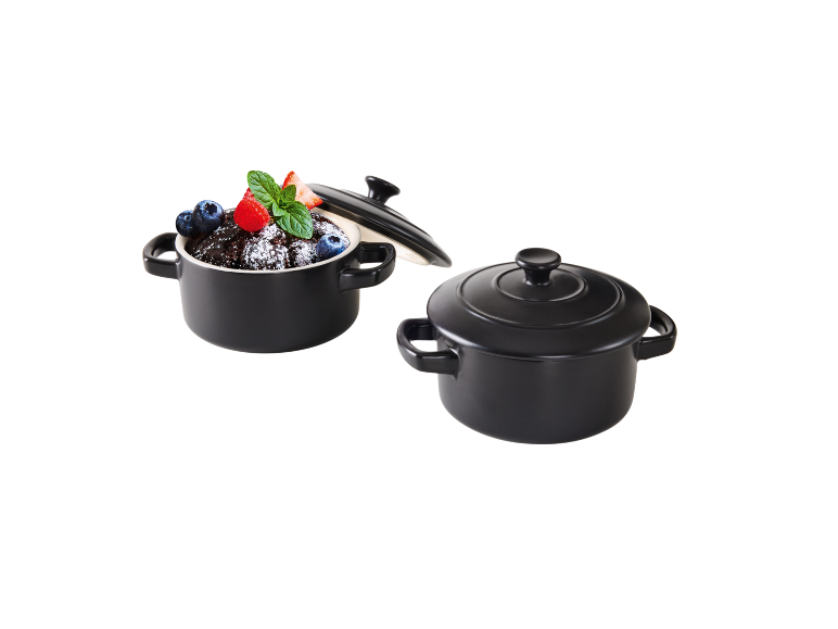 Două oale ceramice negre, una cu desert din fructe de pădure și mentă.