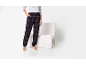 Pantaloni de pijama în carouri închise cu tricou gri și manșete, lângă un fotoliu alb.