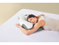 Femeie dormind pe o parte pe o pernă ergonomică albă și gri în pat.