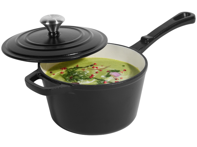 Oală neagră din fontă cu supă verde și condimente.