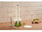 Blender de mână crem cu accesoriu tocător, busuioc și brânză pe un tocător de lemn.