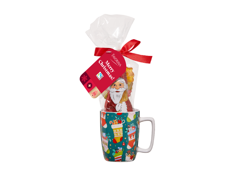 Cană de Crăciun cu Moș Crăciun din ciocolată și dulciuri, cu etichetă roșie 'Merry Christmas!'. 