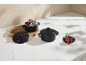 Mini cocotte ceramice negre cu capace, una umplută cu un desert de ciocolată și fructe de pădure.