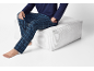 Bărbat în pijama albastră în carouri și tricou albastru închis, așezat pe un puf alb.