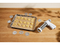 Biscuiți cruzi de diverse forme pe o tavă de copt cu hârtie de copt și presă de biscuiți cu discuri.
