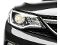 Farul unui automobil negru lucios cu luminile aprinse.
