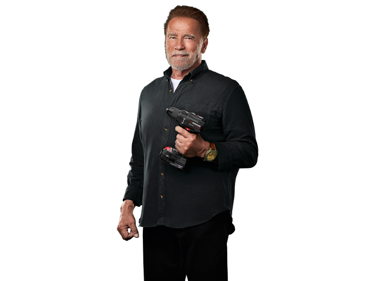 Arnold Schwarzenegger ține o mașină de înșurubat fără fir pe un fundal negru.