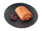 Croissant cu ciocolată și bucăți de ciocolată pe o farfurie închisă.
