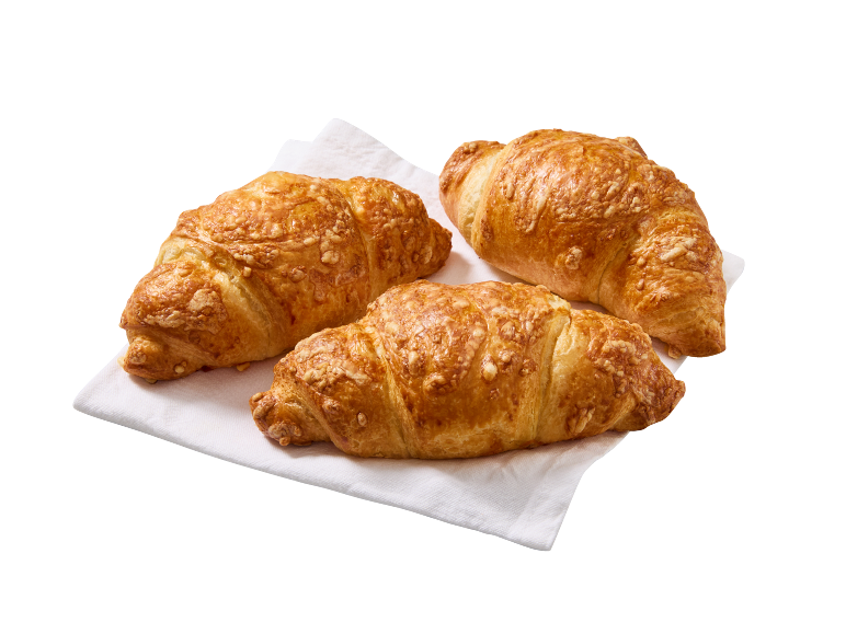 Trei croissante aurii cu brânză pe un șervețel alb de hârtie.