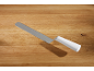 Spatulă de bucătărie cu scară de măsurare și mâner alb pe o suprafață de lemn.
