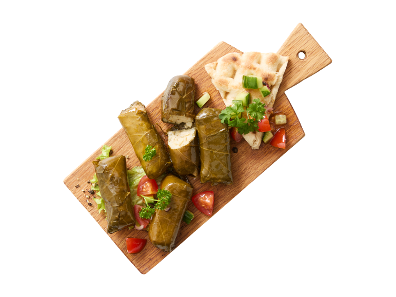 Frunze de viță de vie umplute (dolmades) cu salată proaspătă și lipie pe un tocător de lemn.