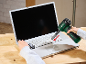 Suflantă fără fir curățând tastatura unui laptop, cu o furculiță în cealaltă mână.