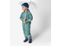 Băiat în salopetă impermeabilă verde, căciulă albastră și cizme de ploaie, ținând o umbrelă.