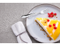 Cheesecake cu jeleu de lămâie, coacăze roșii și furculiță pe o farfurie.