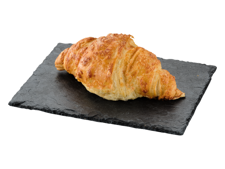 Croissant auriu cu brânză pe o placă de piatră închisă.
