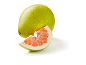 Pomelo verde întreg și o felie de pomelo roz pe un fundal alb.