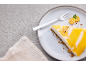 Cheesecake cu lămâie și glazură, furculiță și kumquat pe o farfurie.