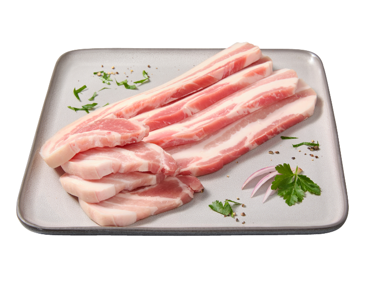 Felii de burtă de porc crudă cu ierburi și ceapă pe o farfurie.
