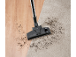 Cap de aspirator pe covor și podea de lemn cu murdărie