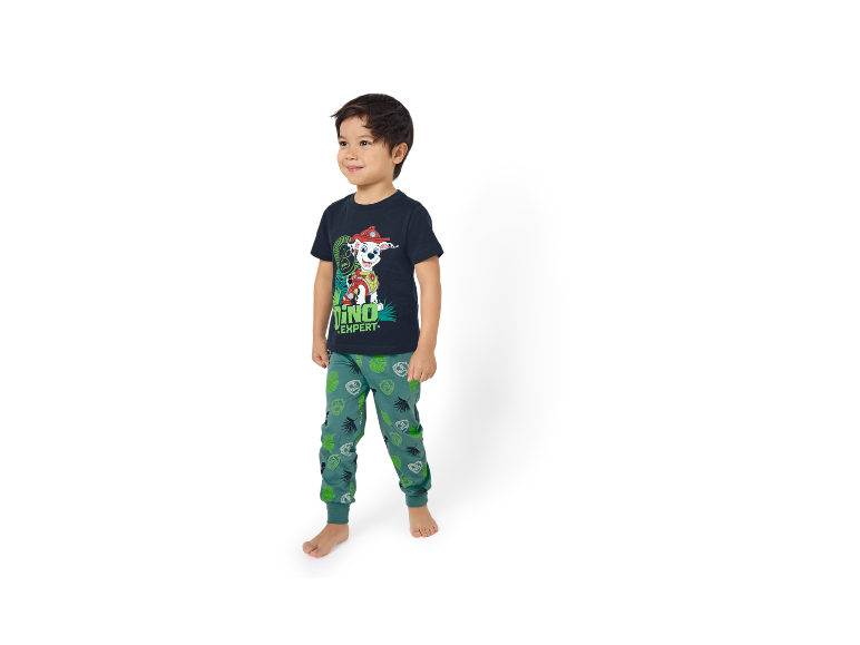 Băiețel în tricou albastru închis cu un câine de desene animate și pantaloni de trening verzi cu tematică dinozauri.