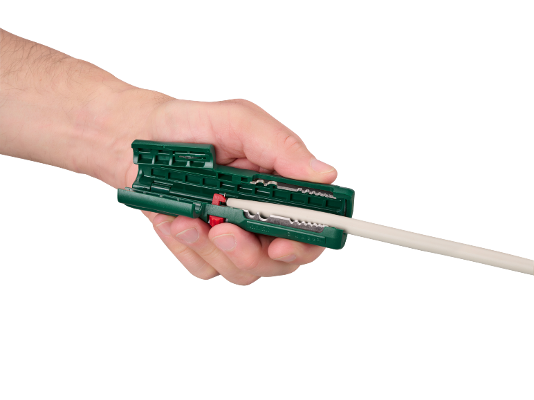 Mână care ține un dezizolator de cabluri verde cu un cablu alb introdus.