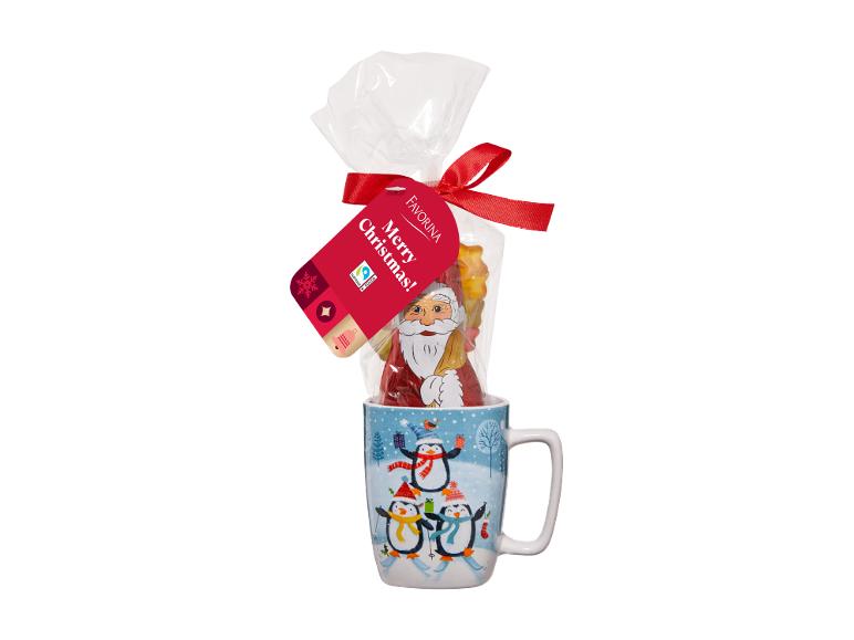 Cană de Crăciun cu pinguini, conținând un Moș Crăciun din ciocolată și dulciuri, cu eticheta „Merry Christmas!”.