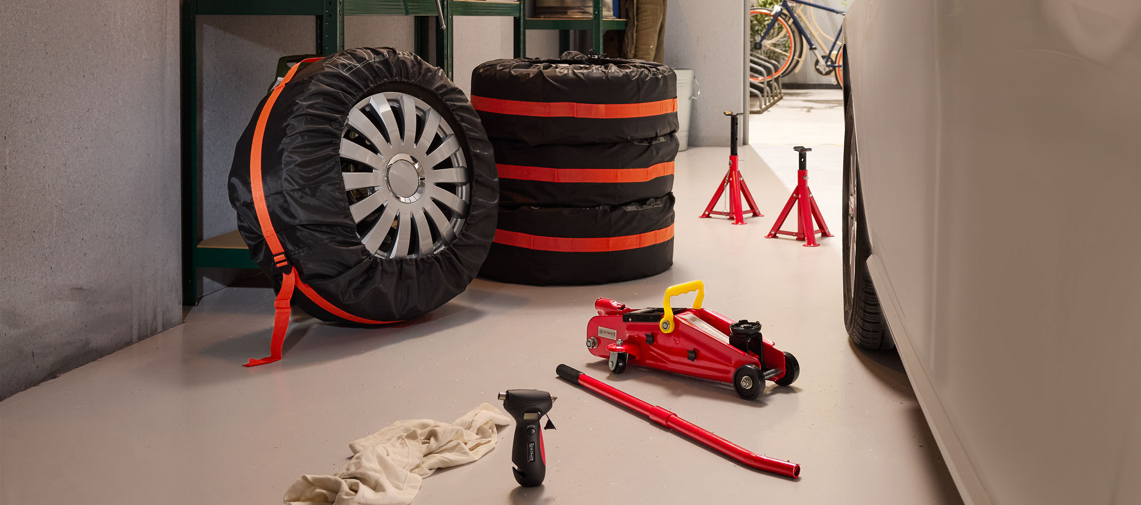 Anvelope auto cu huse, cric și suporți într-un garaj.