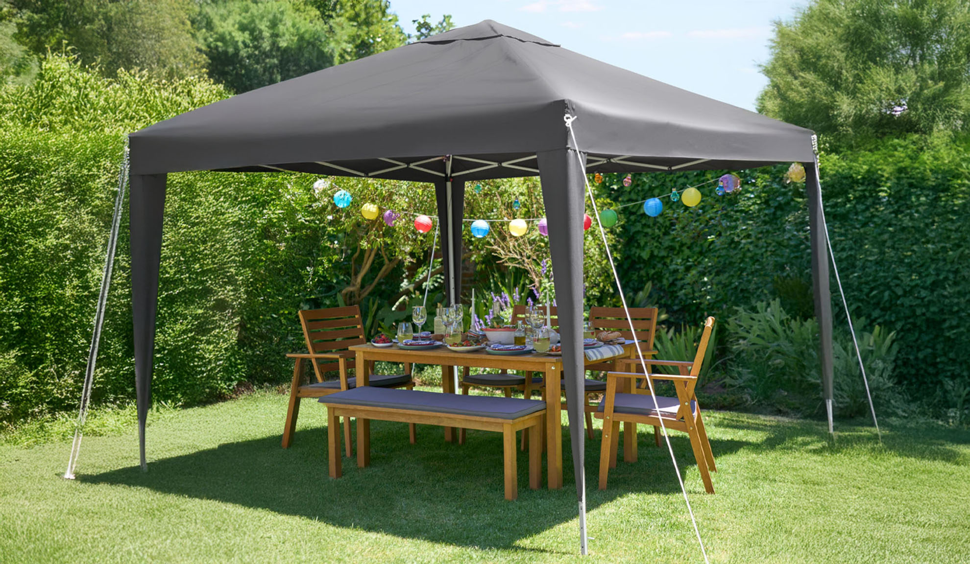 Gazebo de grădină gri închis cu masă și scaune din lemn.