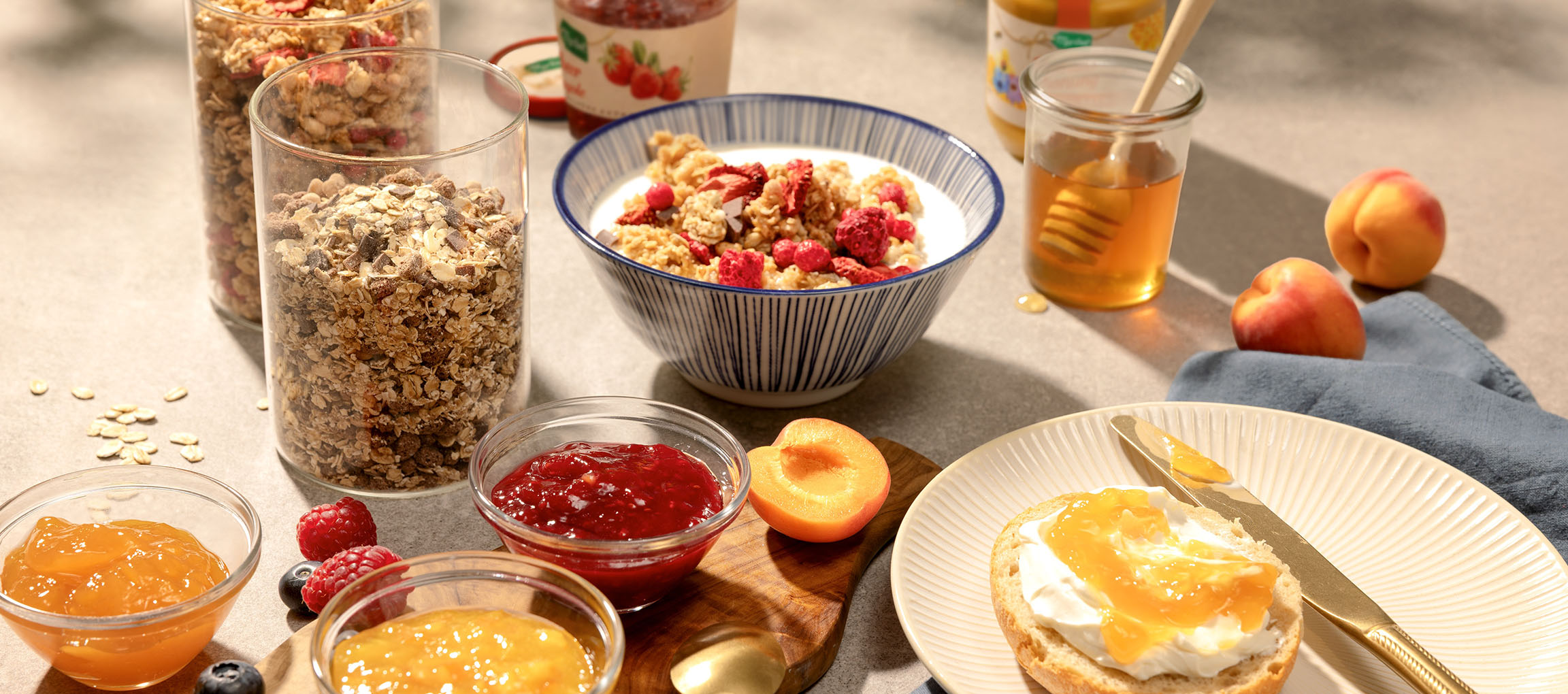 Micul dejun cu granola, lapte, miere, gemuri și o chiflă cu cremă de brânză.