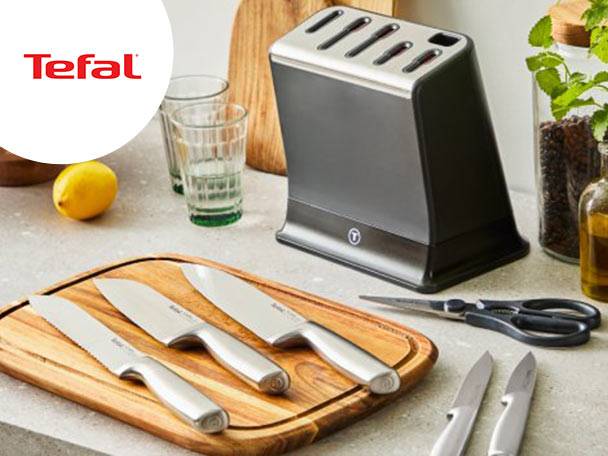 Set de cuțite de bucătărie cu suport, foarfece și tocător din lemn pe un blat de bucătărie.