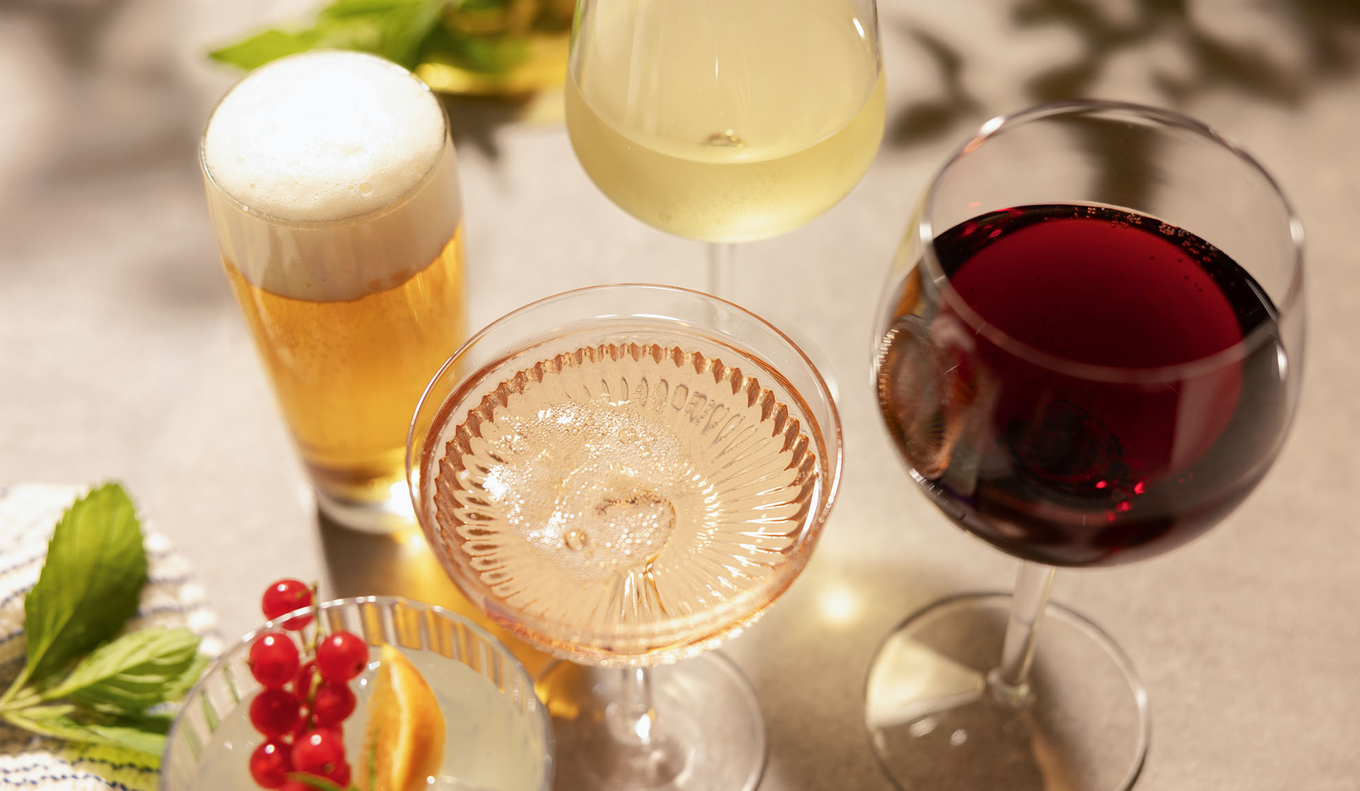 Pahare de bere, vin alb, rosé și roșu, cu un cocktail și fructe de pădure.