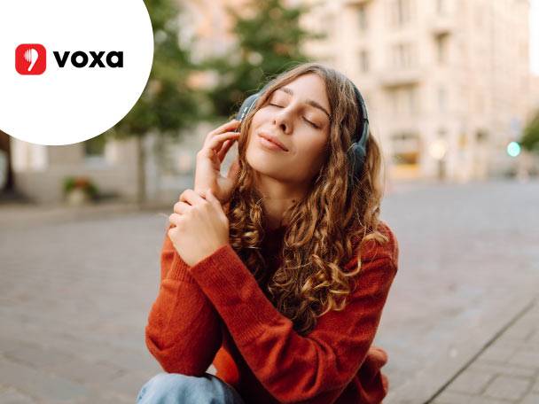O femeie cu căști, cu ochii închiși, ascultând muzică, cu logo-ul Voxa în colț.