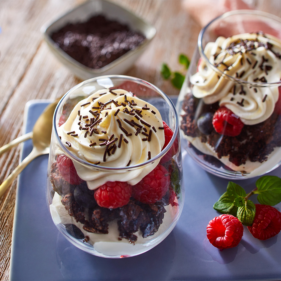 Deserturi cu ciocolată, zmeură și frișcă, decorate cu fulgi de ciocolată.