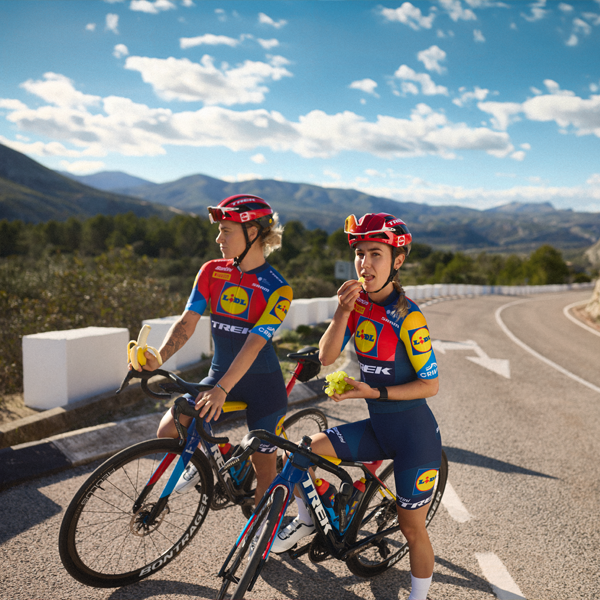 Două cicliste din echipa Trek-Segafredo Lidl se bucură de o pauză cu fructe.