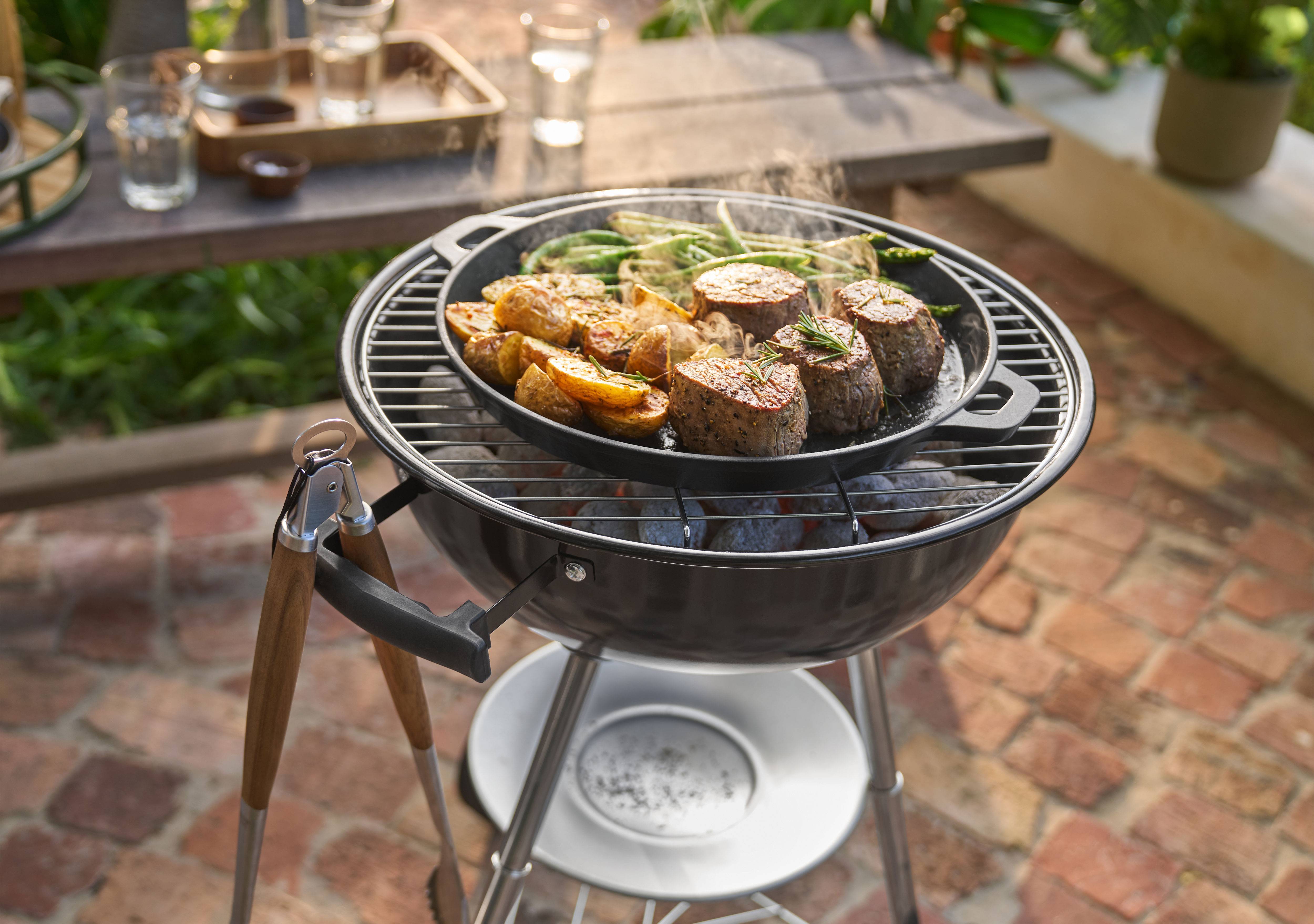 Grătar cu carne, cartofi și fasole verde gătite într-o tigaie în aer liber.